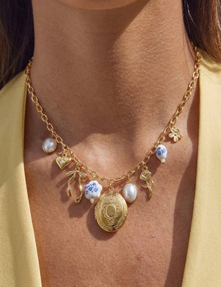 Gold necklace with charms on a person wearing a yellow top